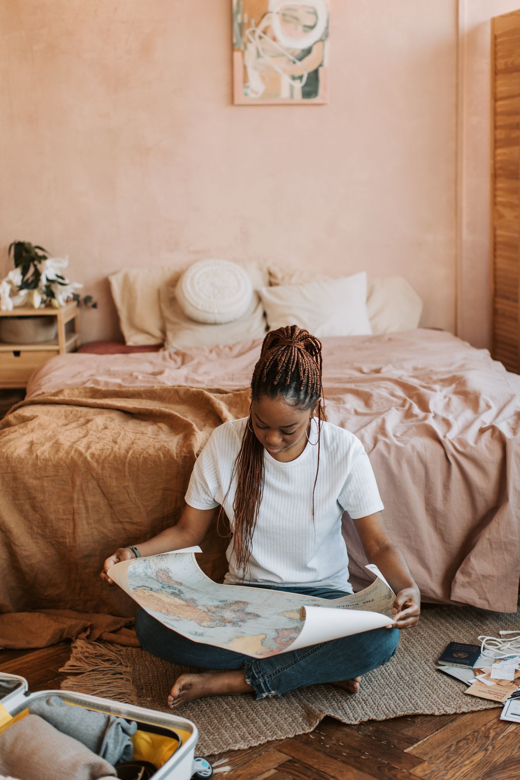 Black Women Travelers Deserve More Space - A woman in a cozy bedroom looking at a map while preparing for her trip.