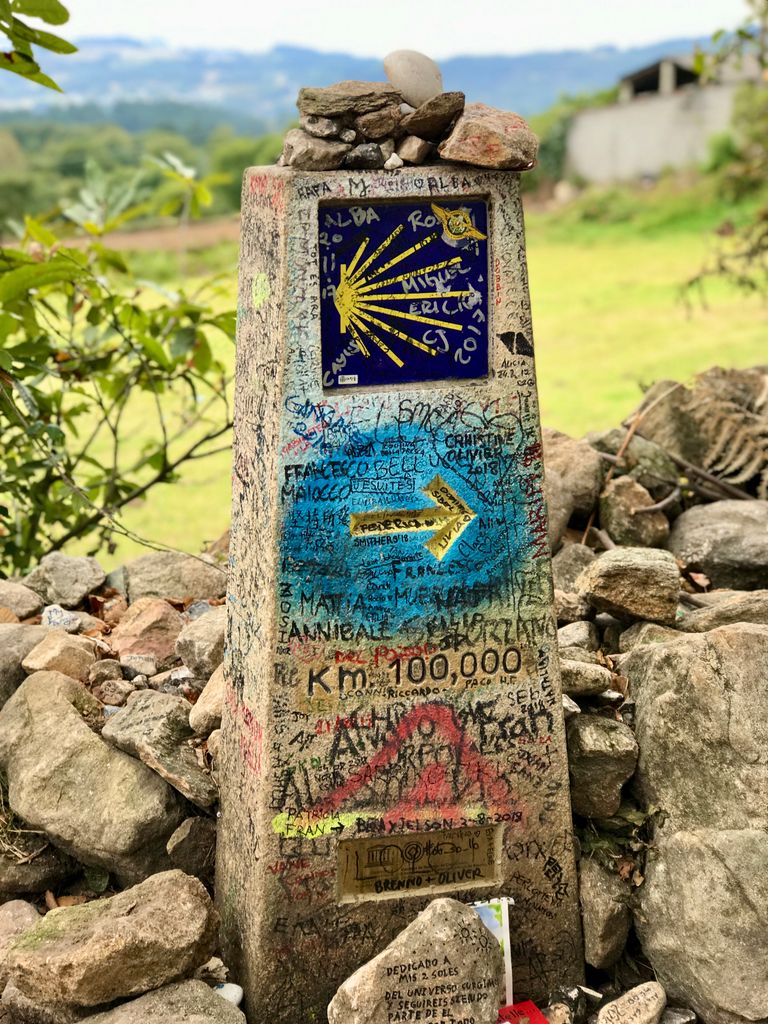 Camino Glossary: Words Every Pilgrim Should Know - Stone milestone with Camino de Santiago sign in Paradela, Spain.