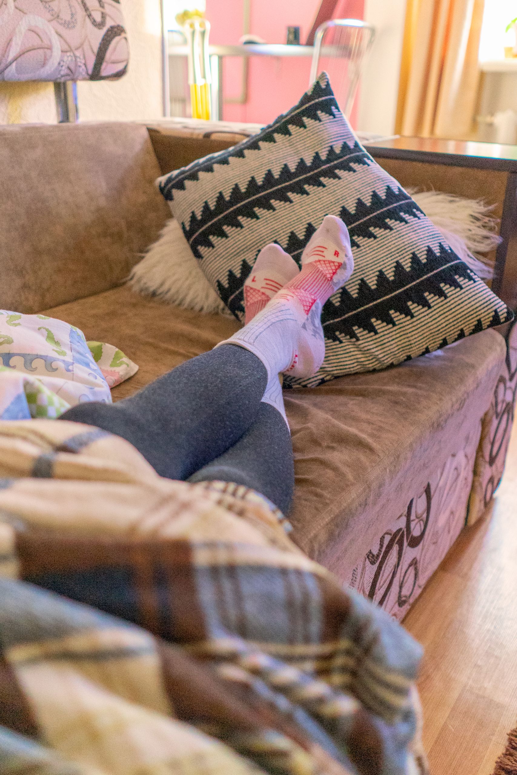Clean Socks - A person relaxing on a sofa with warm socks and a plaid blanket, enjoying a peaceful indoor day.