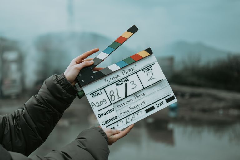 Close-up of a film clapperboard on an outdoor set, signaling scene start.