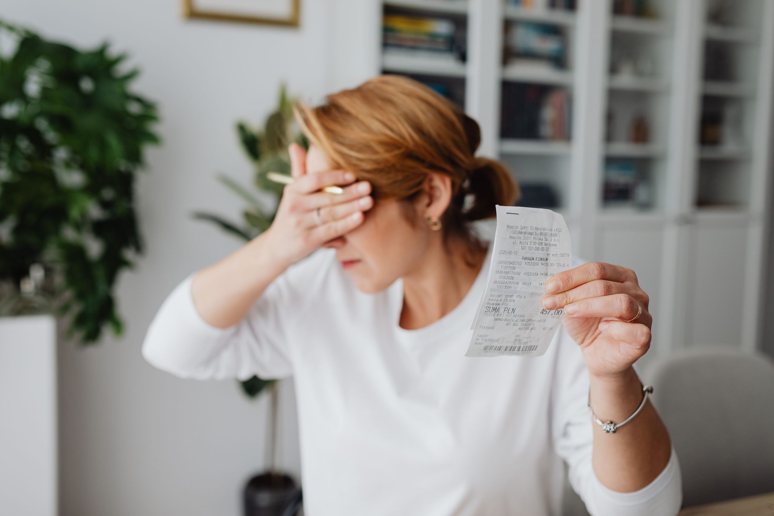 Debt - Woman experiencing stress while reviewing household expenses at home.