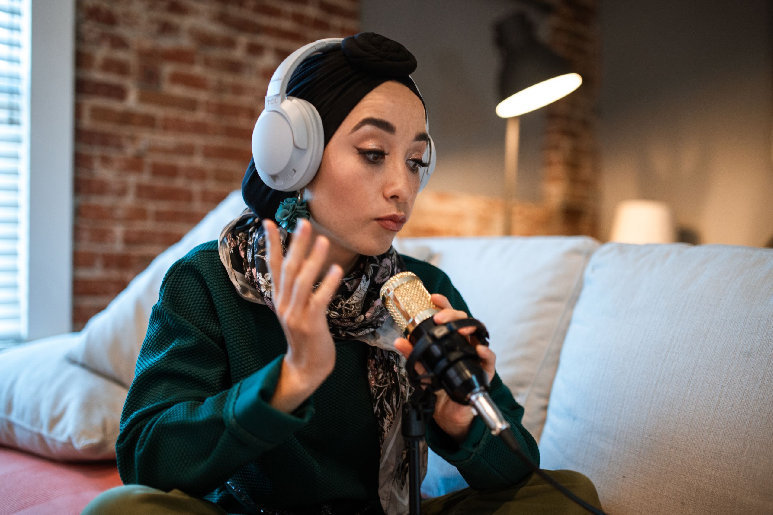 Finding My Voice: Empowerment Through Storytelling - Young woman podcasting with headphones and a microphone indoors.