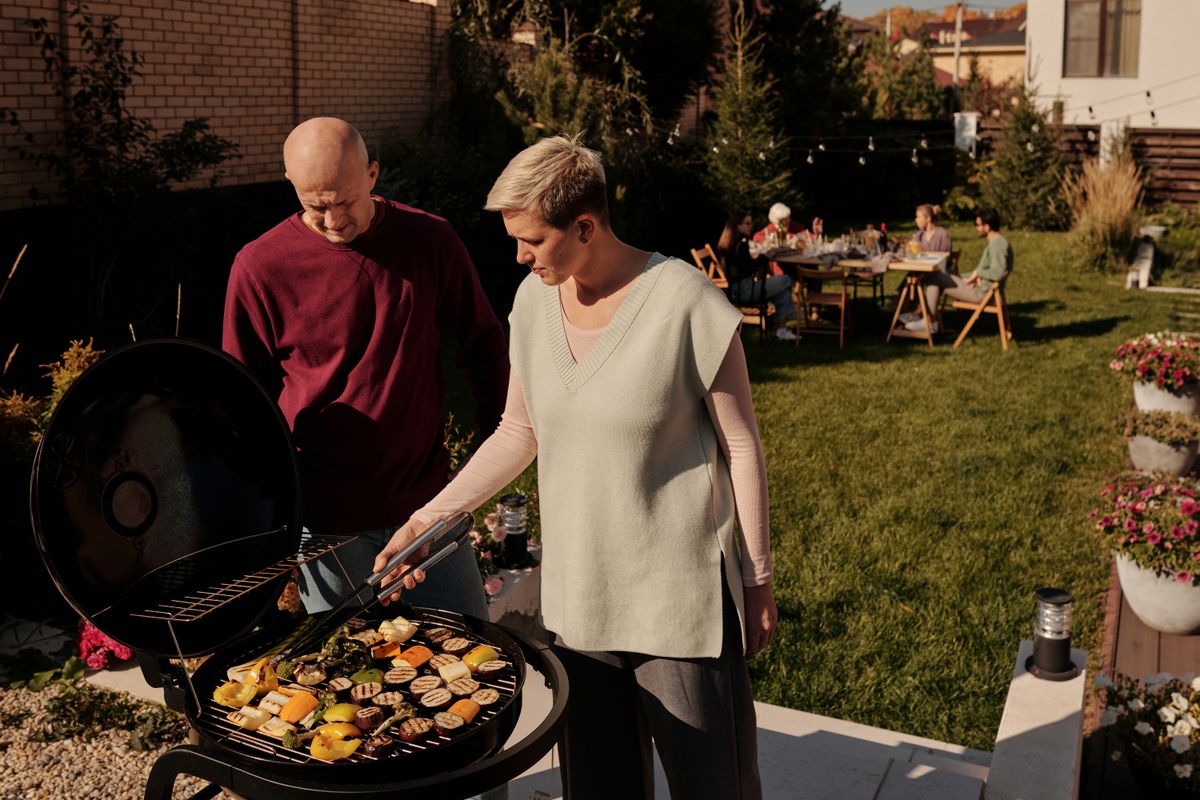 Fire Grill Essential Gear - Couple grilling vegetables at a backyard barbecue gathering.