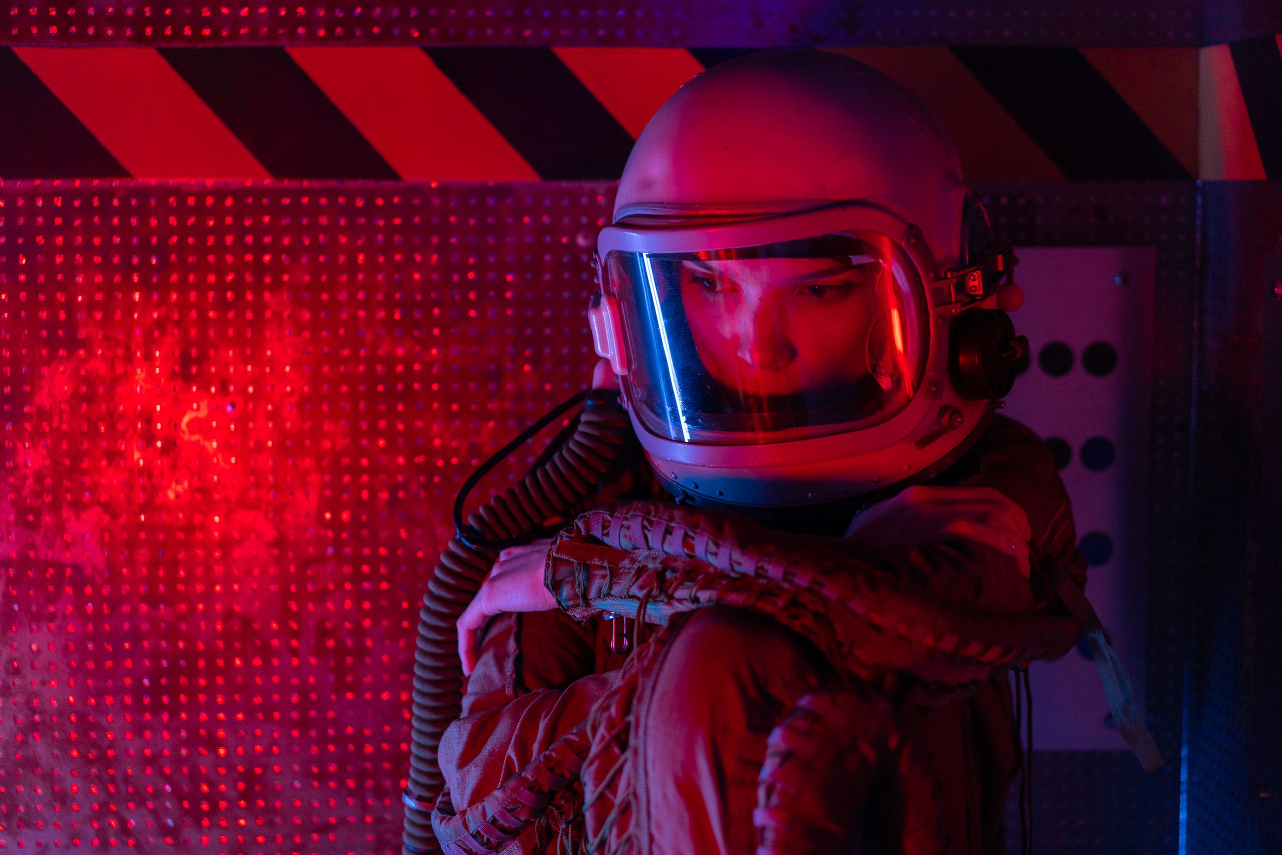 Gender Portrayal in Sci-Fi Films - Astronaut in space suit sitting thoughtfully in red futuristic setting.
