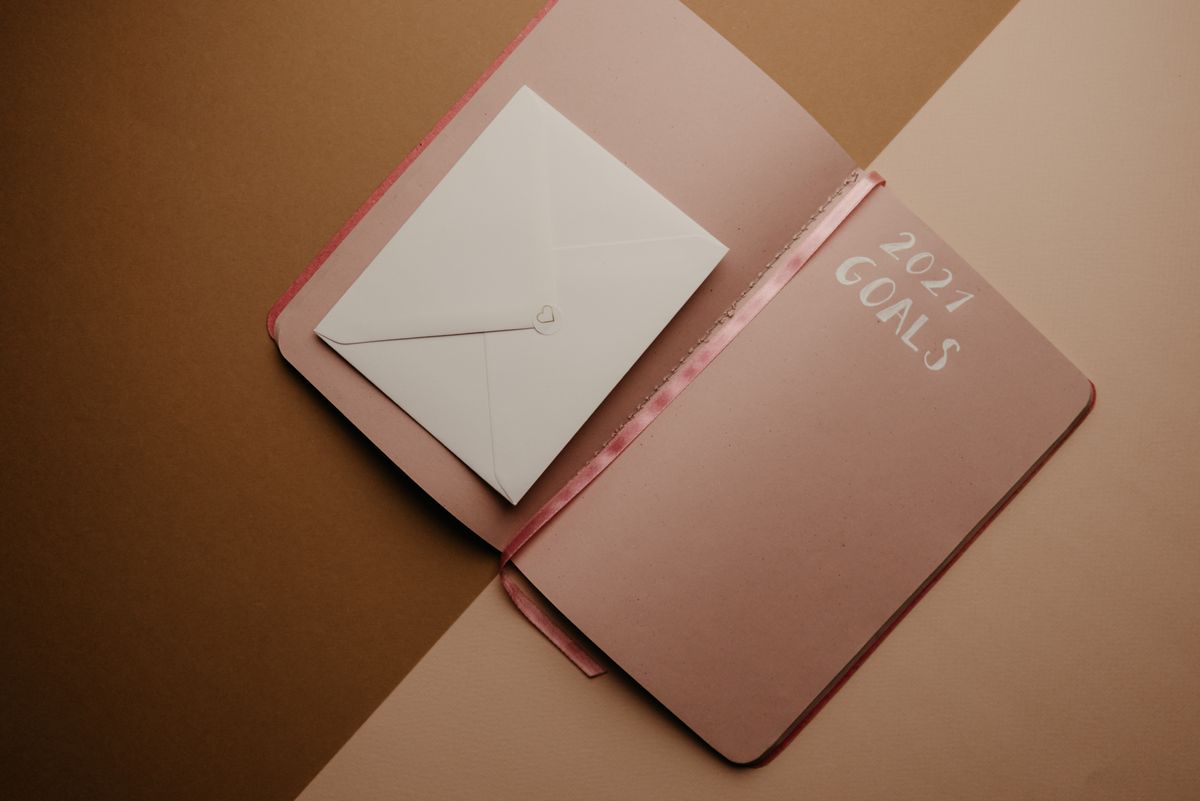 How to Set SMART Goals for Your Life - Flat lay of 2021 goals planner and envelope on a stylish brown background, perfect for planning imagery.