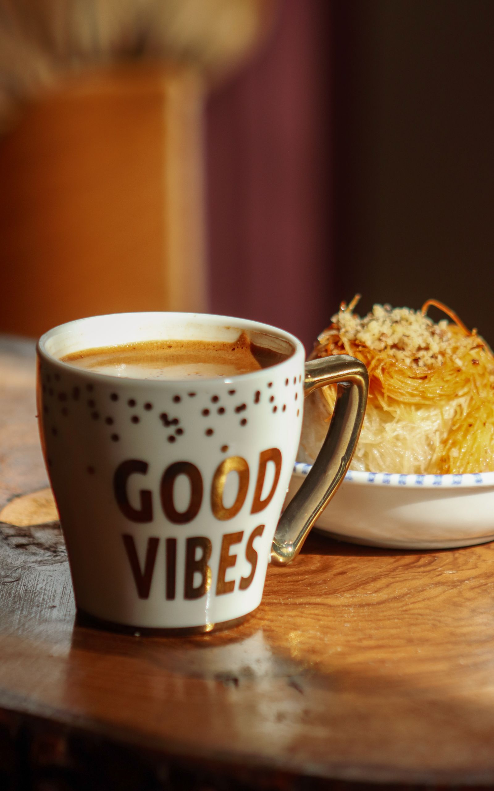 Let Good Things Be Good - A cozy coffee cup with 'Good Vibes' and a delicious pastry on a wooden table.