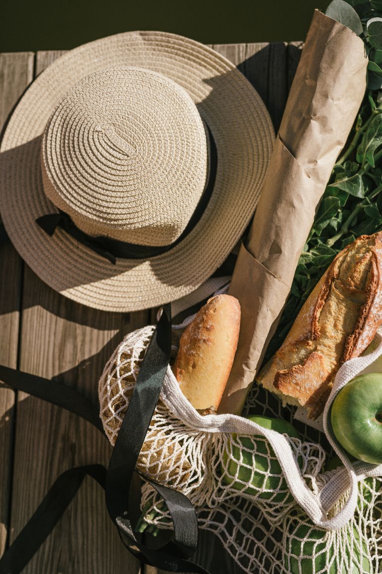 My Farmers Market Bag Always Tells the Truth - Top view of summer picnic items including a hat, baguette, and fruit on a wooden pier.