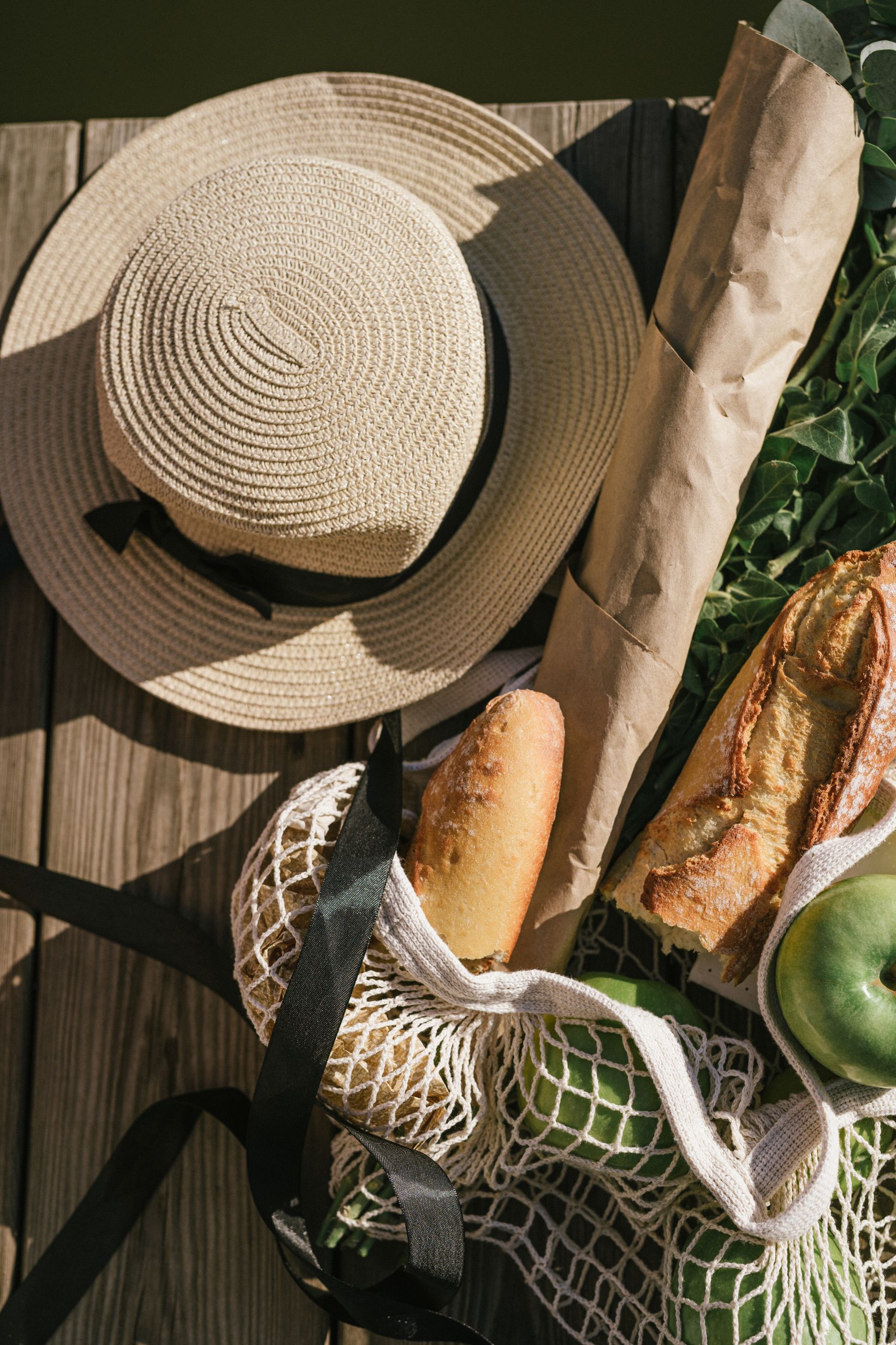 My Farmers Market Bag Always Tells the Truth - Top view of summer picnic items including a hat, baguette, and fruit on a wooden pier.