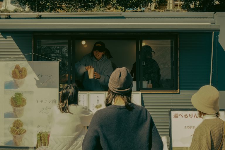 People enjoying street food at an outdoor vendor booth in Toyota, Aichi, Japan.