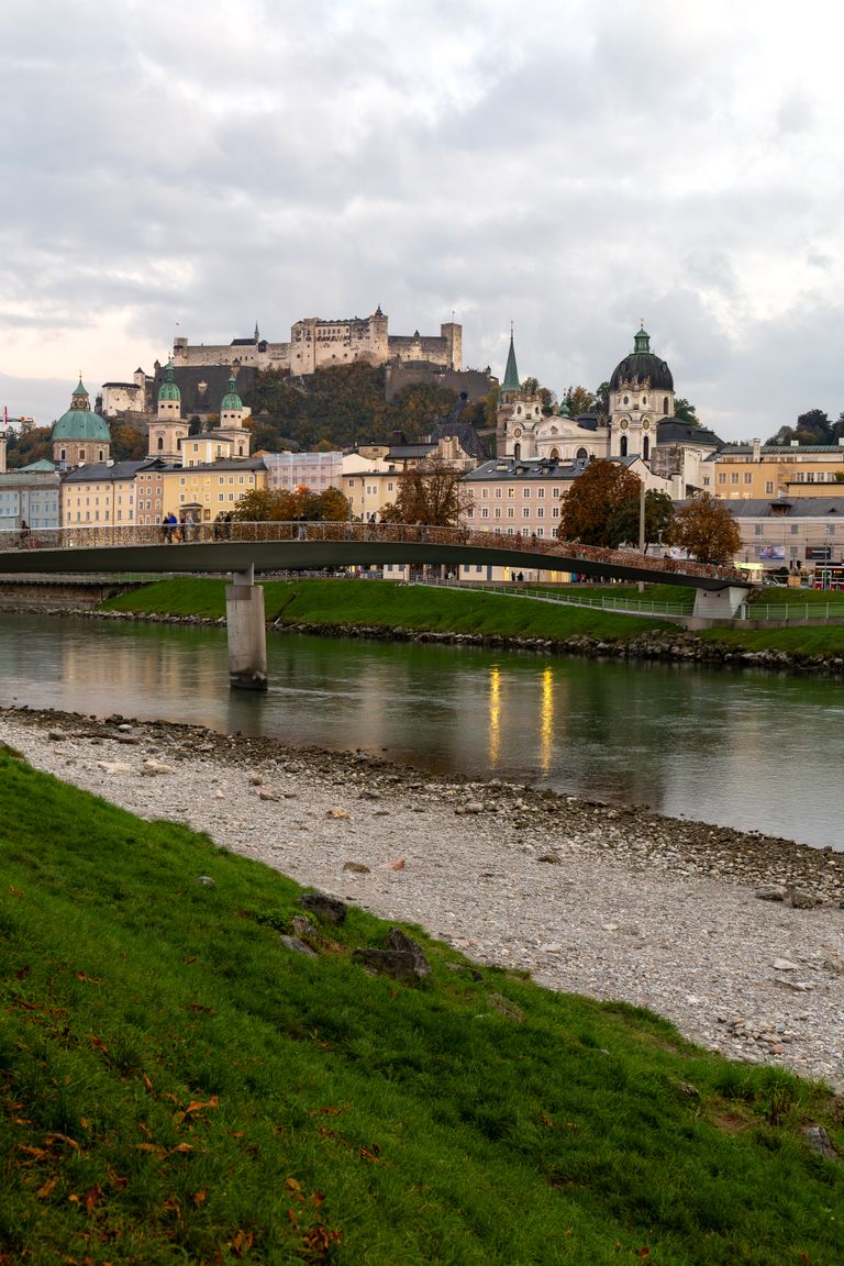 Sound of Music -Picturesque autumn landscape in Salzburg featuring historic castle, river, and vibrant fall foliage.