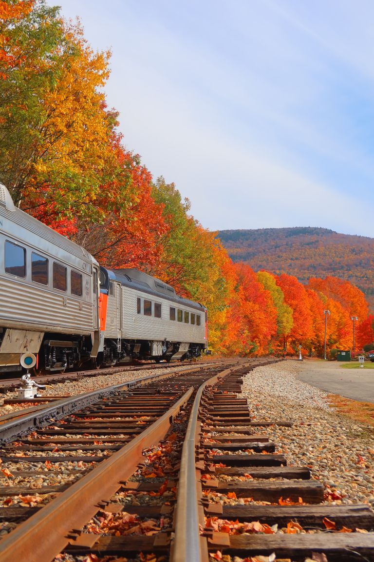 The Beauty of Traveling in a Season of Change - Silver train cruising through vibrant fall foliage in Lincoln, NH, showcasing seasonal beauty.