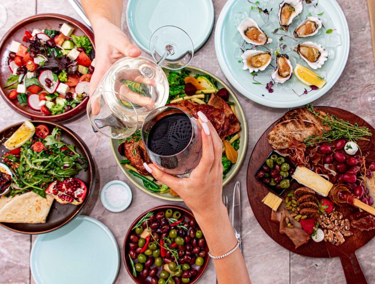 The Long Lunch That Becomes the Whole Point - A top view of a luxurious dining setup featuring gourmet dishes, fresh salads, oysters, and wine.