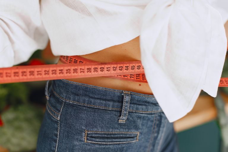 The Progress No One Else Can Measure - Close-up image of a woman measuring her waist with a tape measure, promoting fitness and health goals.