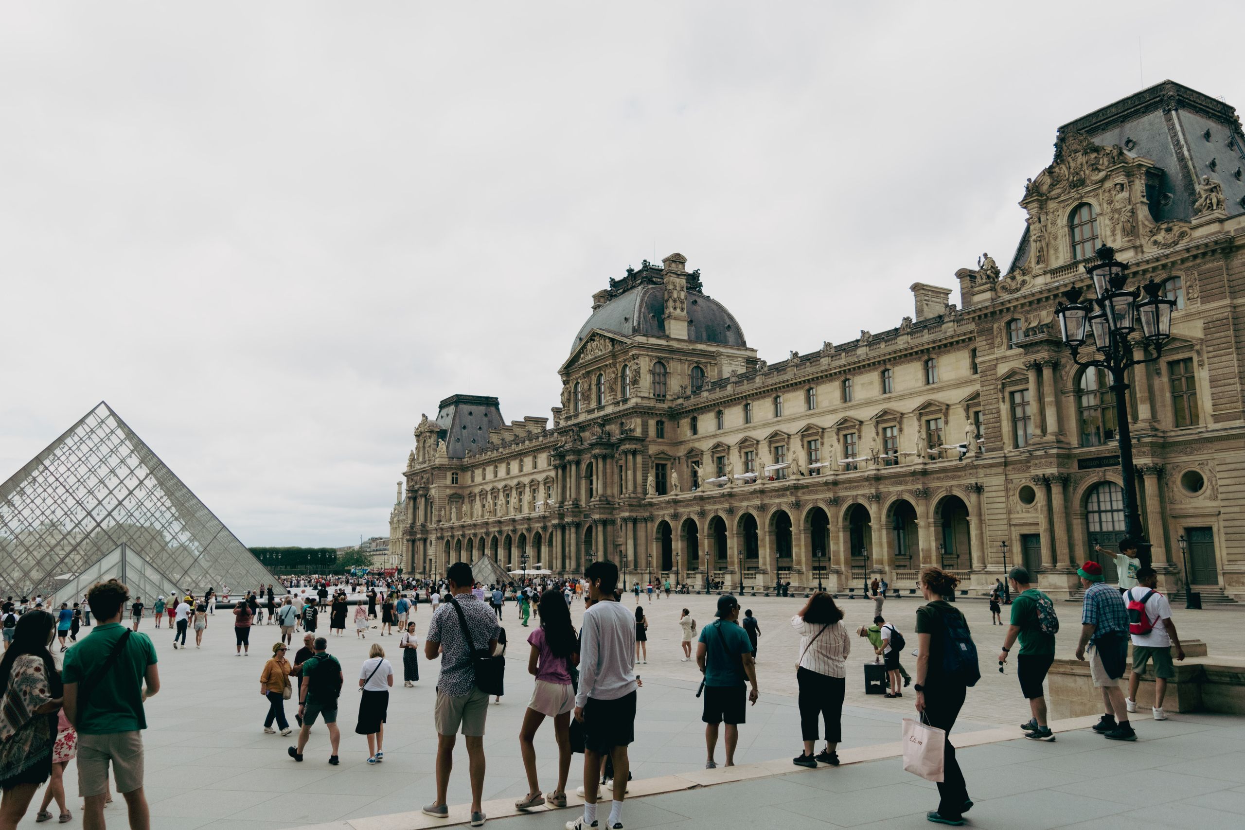The Questions That Changed the Way I Travel - Visitors gather at the Louvre Museum in Paris with the iconic glass pyramid in view.