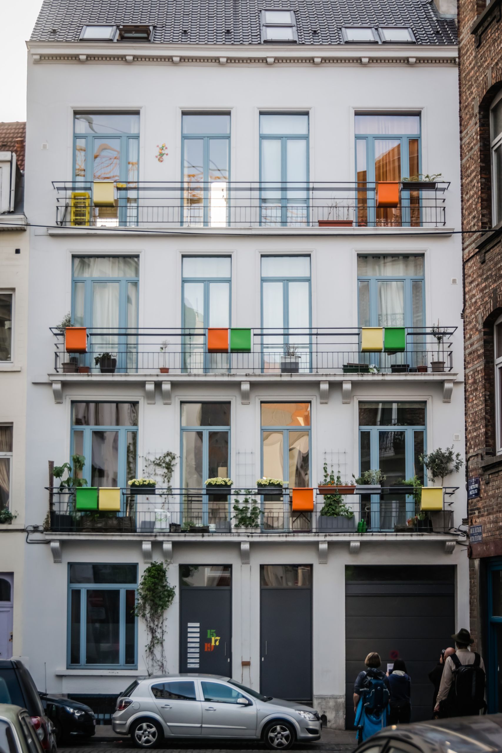 The Shape of a City Block Changes the Story - Charming facade of a city apartment building with colorful balconies and windows.