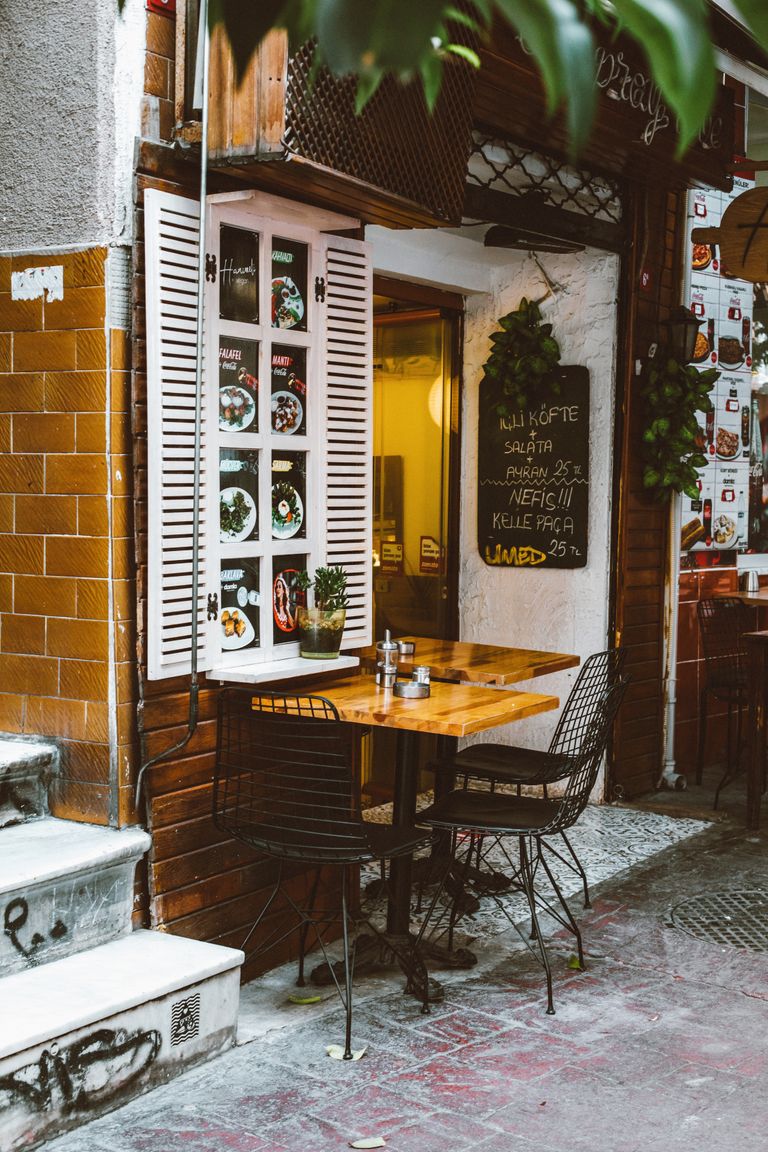 The Small Restaurant Table That Tells the Truth - Charming urban café with outdoor seating, inviting atmosphere, and decorative menu display.