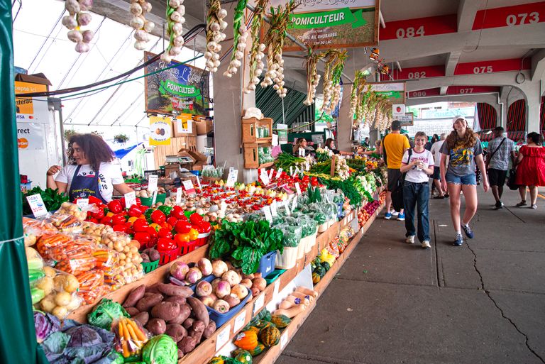 The Story Changes the Meal - Colorful farmers market scene with a variety of fresh vegetables and shoppers exploring the stalls.