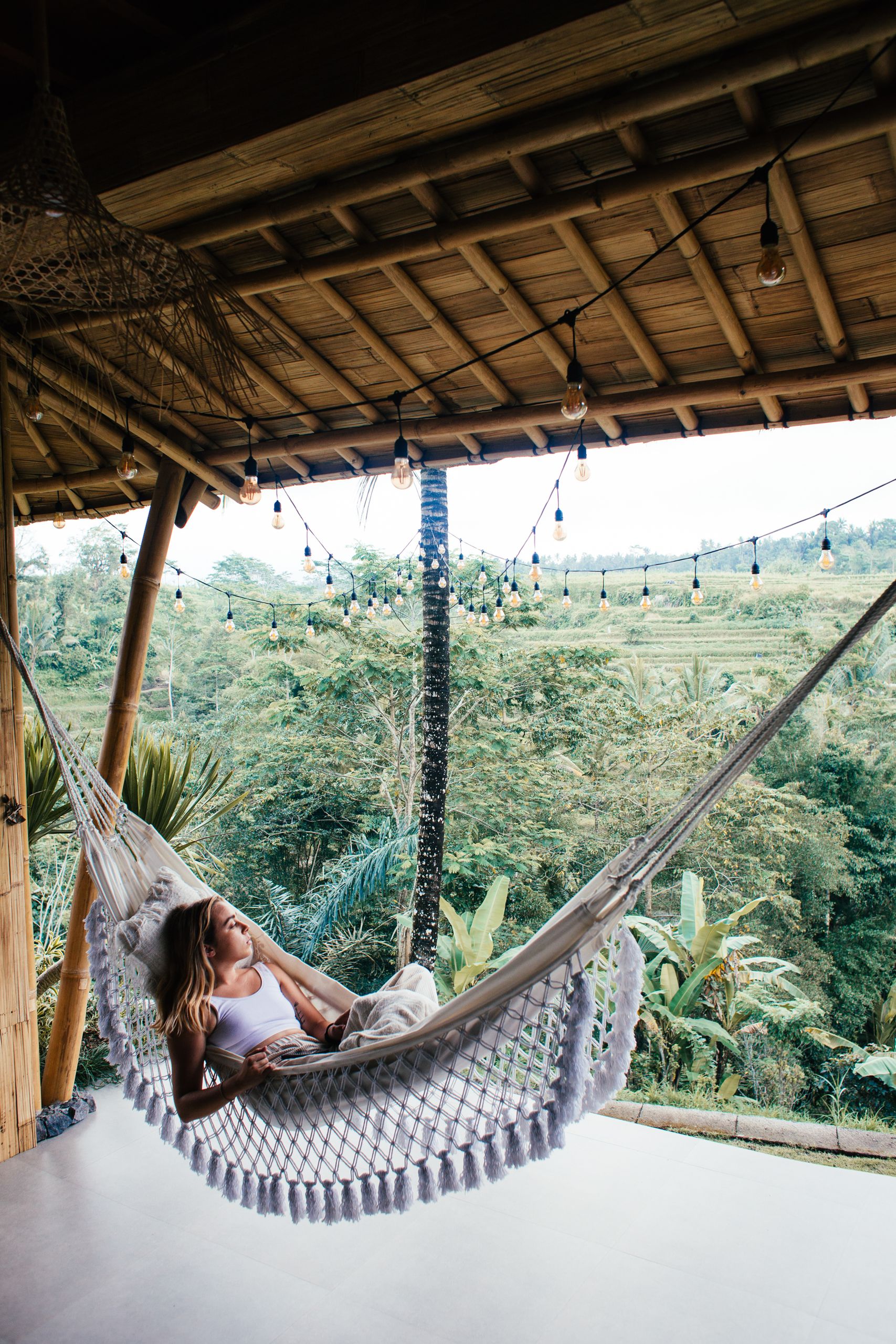 The Trips That Give Me Time to Hear Myself - Young tourist lying in hammock against tropical plants on bamboo veranda while looking away in daylight