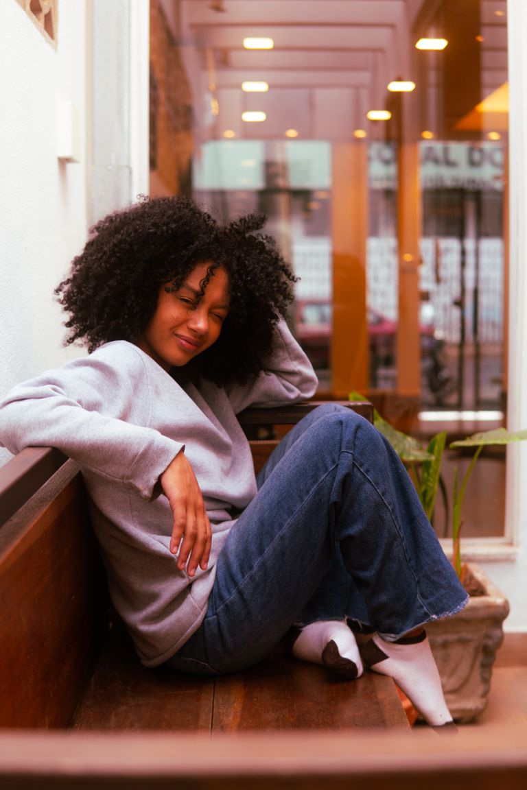 The Women Who Make Events Feel Effortless - The Women Who Make Events Feel Effortless - Woman relaxing casually on a bench indoors, exuding warmth and comfort.