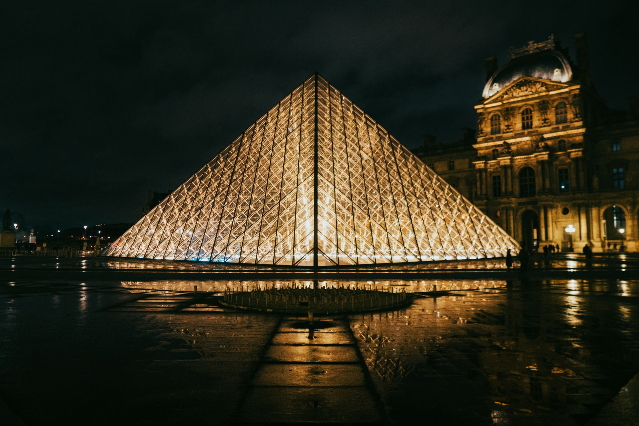 View of the Louvre Pyramid glowing at night, showcasing modern architecture in Paris, France.
