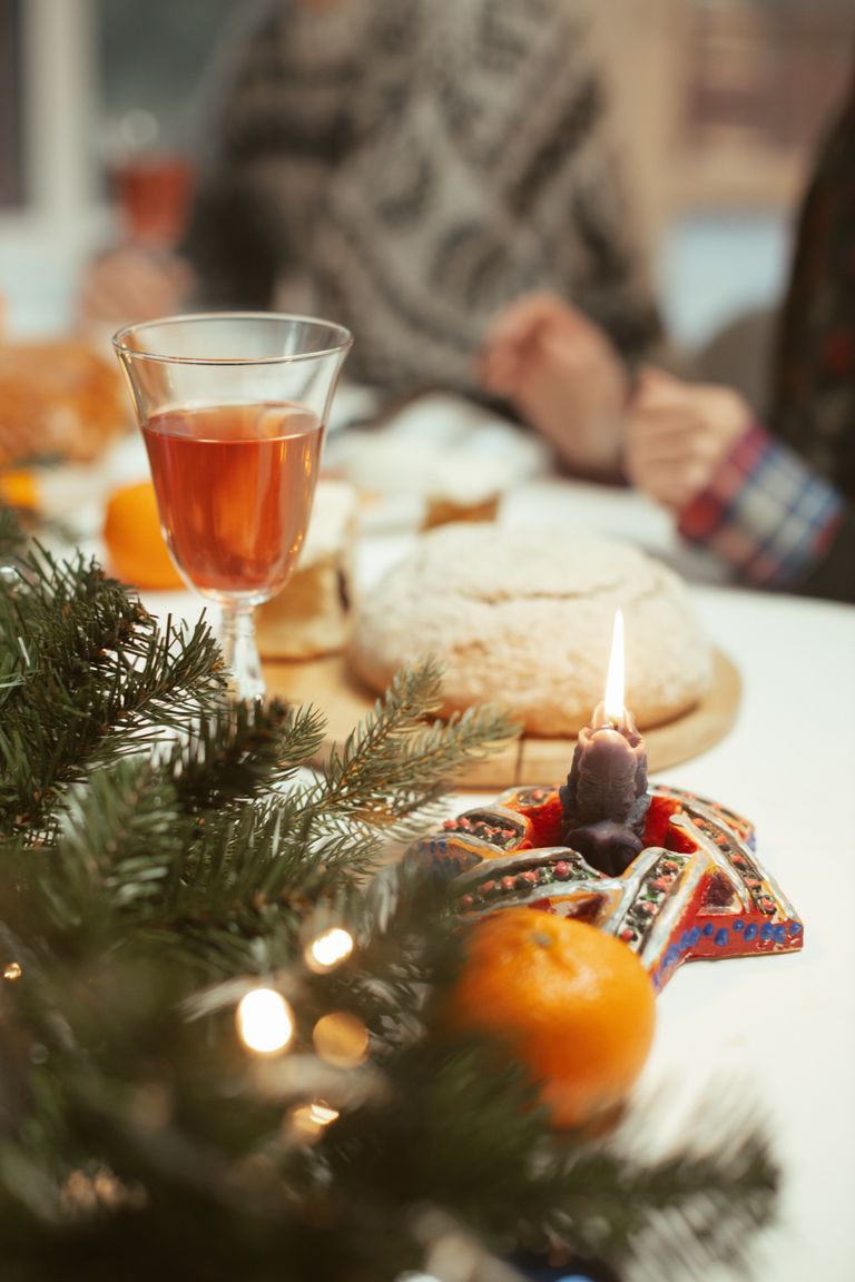 Warm festive table setting with candlelight, pine branches, and a glass of wine. Perfect for holiday celebrations.