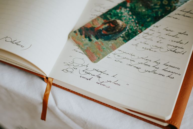 What a Year of Stories Can Teach - A close-up of an open journal with handwritten text and a colorful bookmark, evoking creativity.