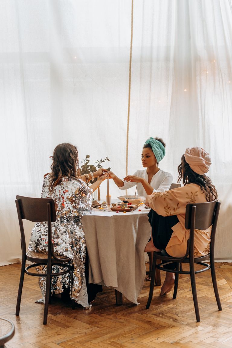 What Women Tell Each Other at the Table - Three women share a meal together at a round table in a cozy indoor setting.