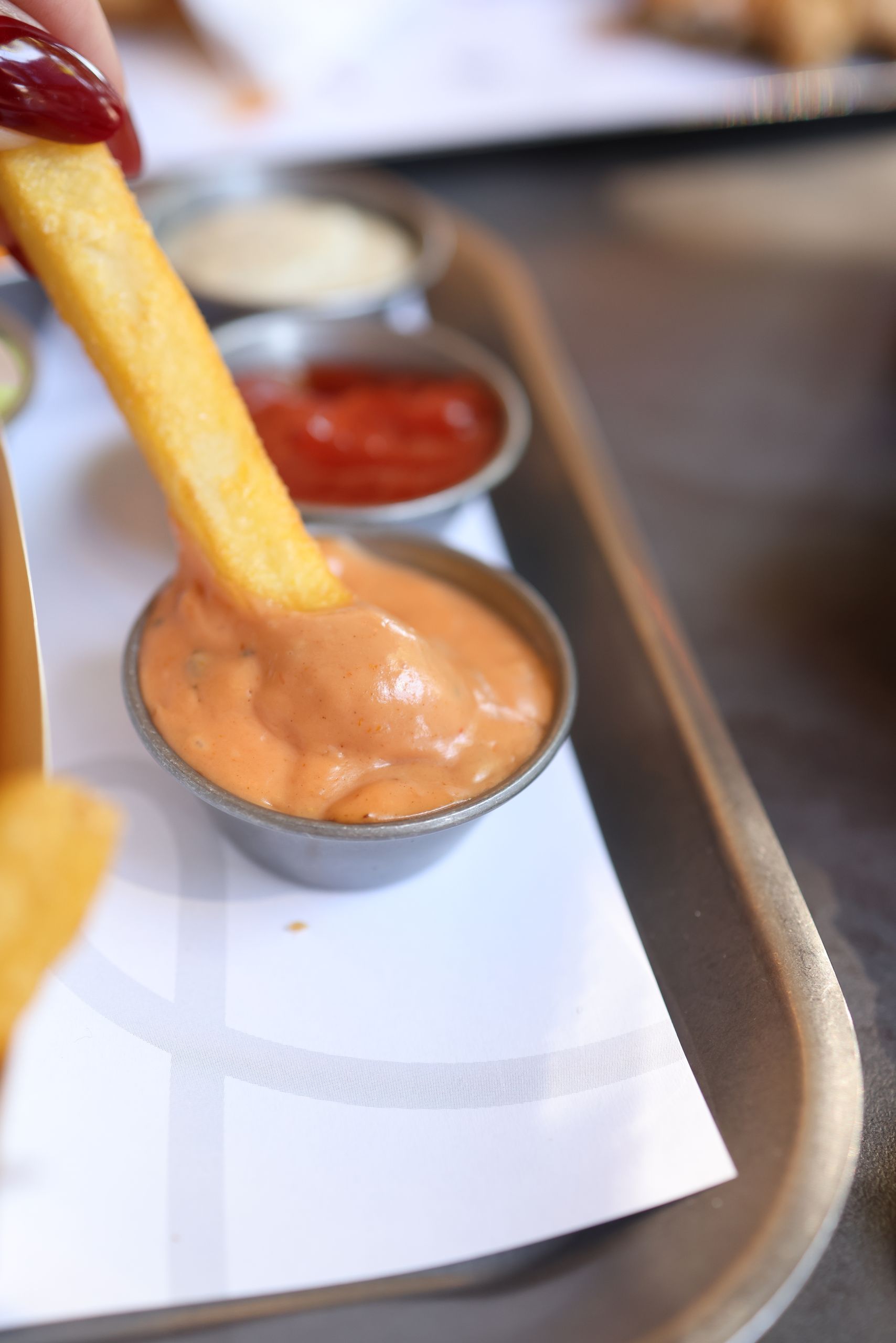 Why I Care About the Sauce on the Side - Close-up of a french fry being dipped into a creamy sauce with other condiments.