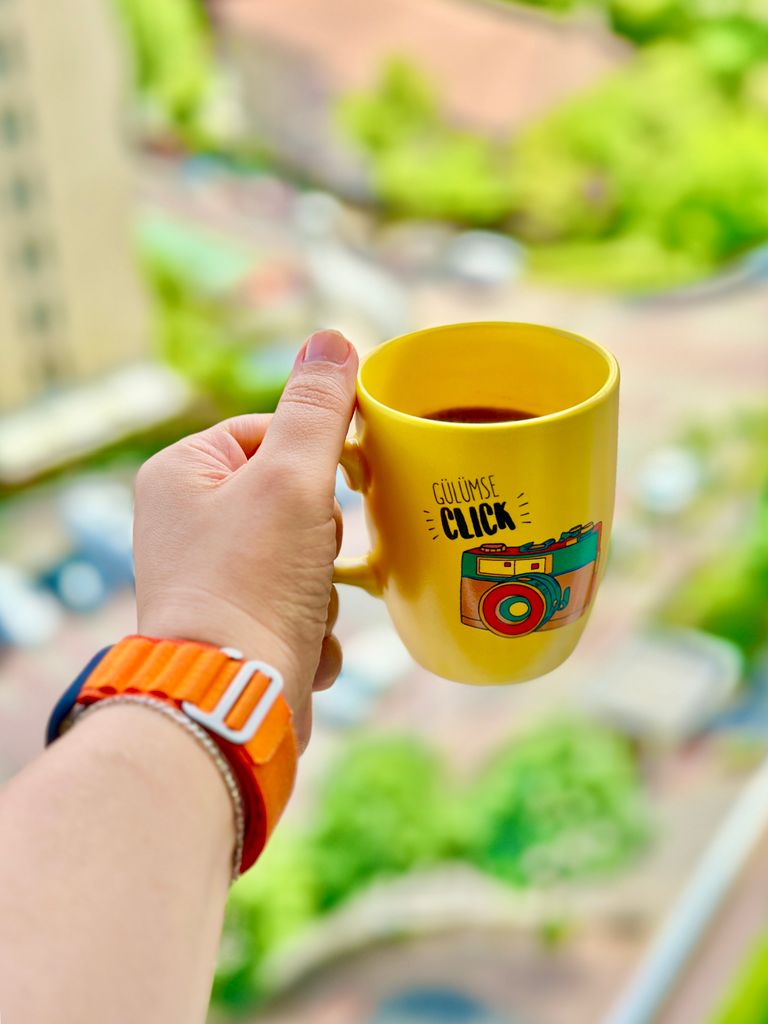 Why I Like Travel Days That Start With Coffee - Colorful yellow mug with coffee in hand overlooking İstanbul view, vibrant and fresh.