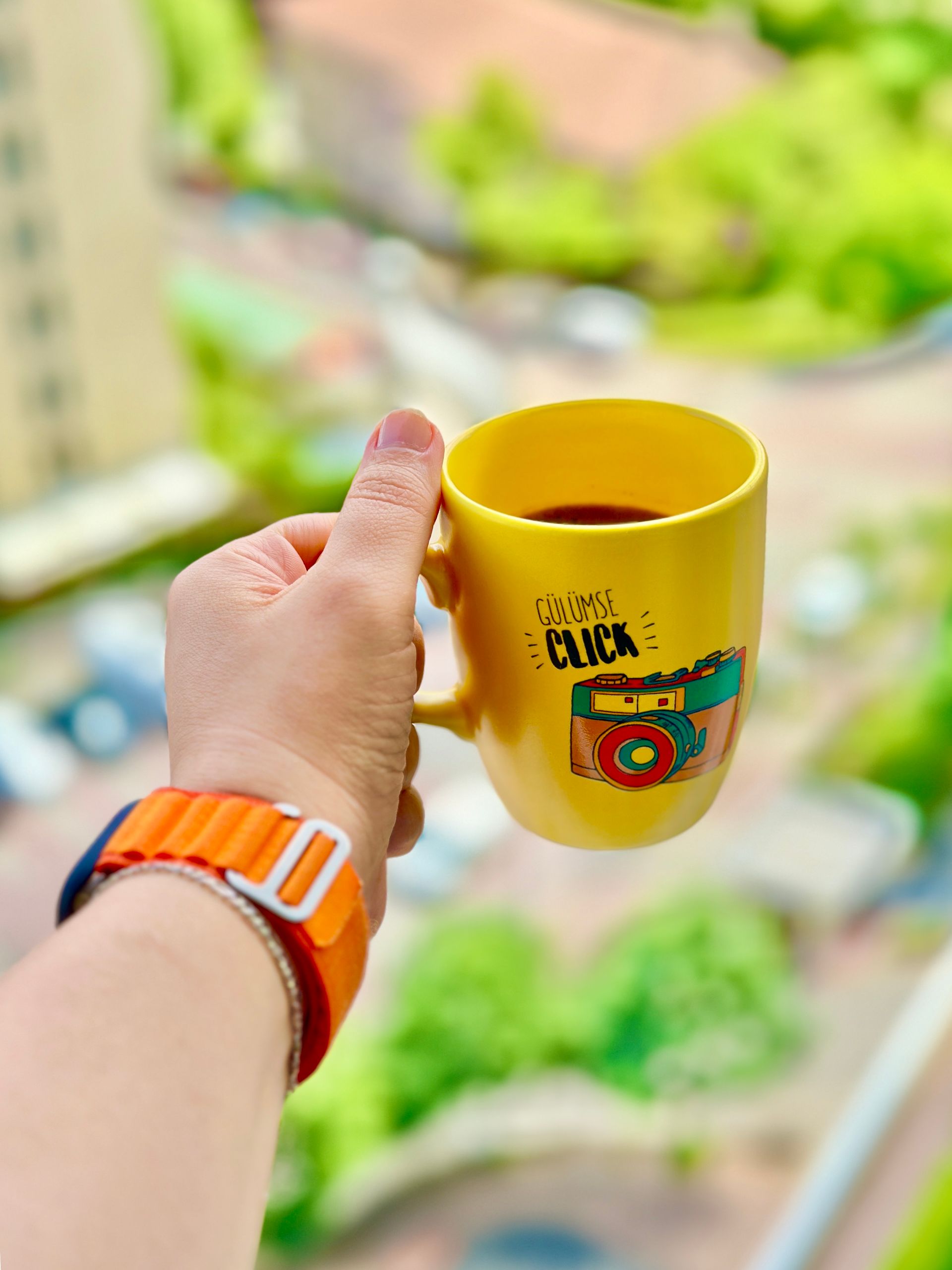 Why I Like Travel Days That Start With Coffee - Colorful yellow mug with coffee in hand overlooking İstanbul view, vibrant and fresh.