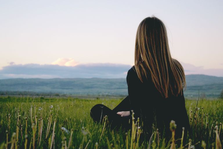Why I Need Space to Change My Mind - Woman enjoying peace in a lush green field with a scenic mountain view during sunset.