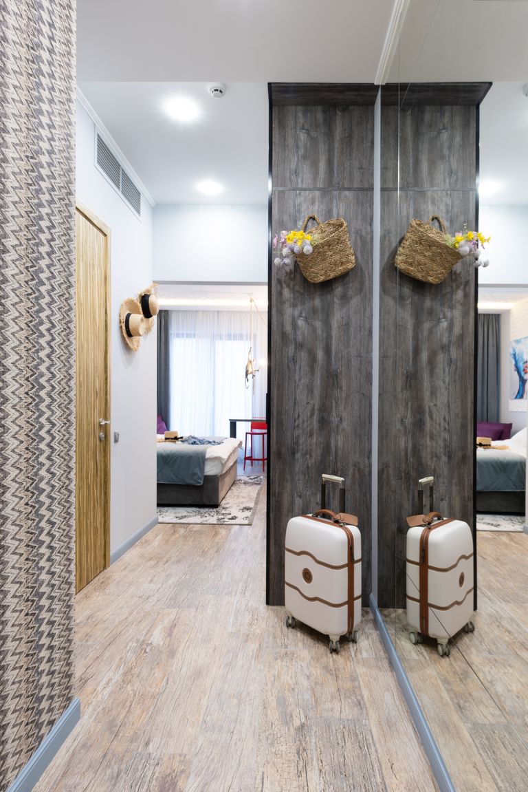 Why I Think Home Has More Than One Meaning - Luggage placed near wall in long corridor of modern hotel room with decoration on wall and bedroom in distance during travelling