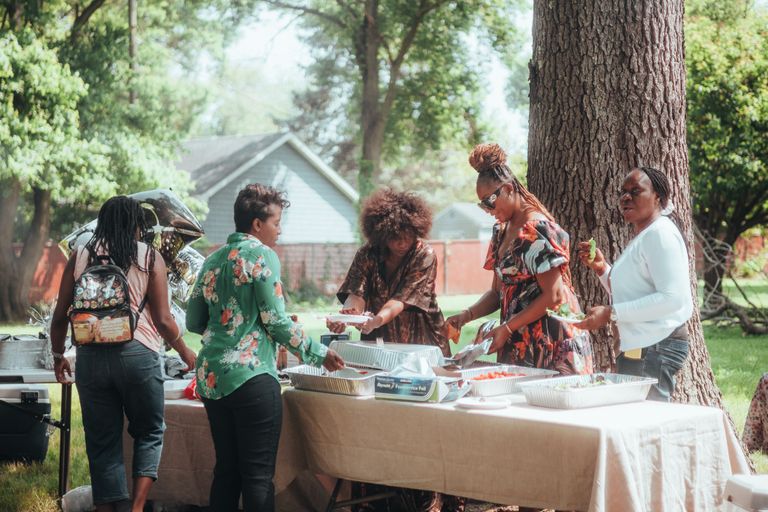 Why Juneteenth Belongs at the Table Too - Group of women enjoying an outdoor buffet in a lush garden setting.