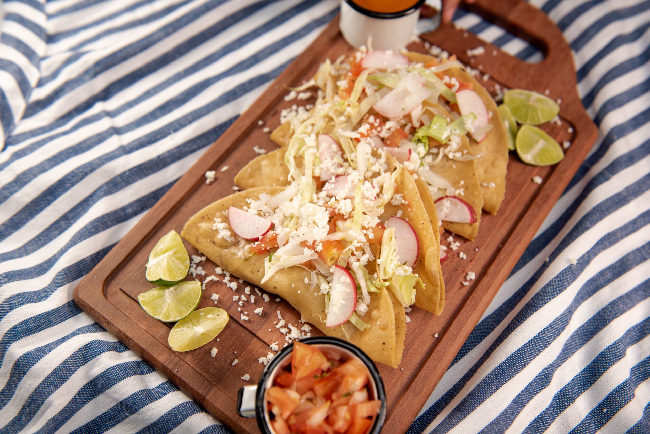 Why Tacos Make the Perfect Picnic Meal - Delicious Mexican tacos served on a wooden platter with fresh limes and toppings. Perfect food photography for culinary blogs.