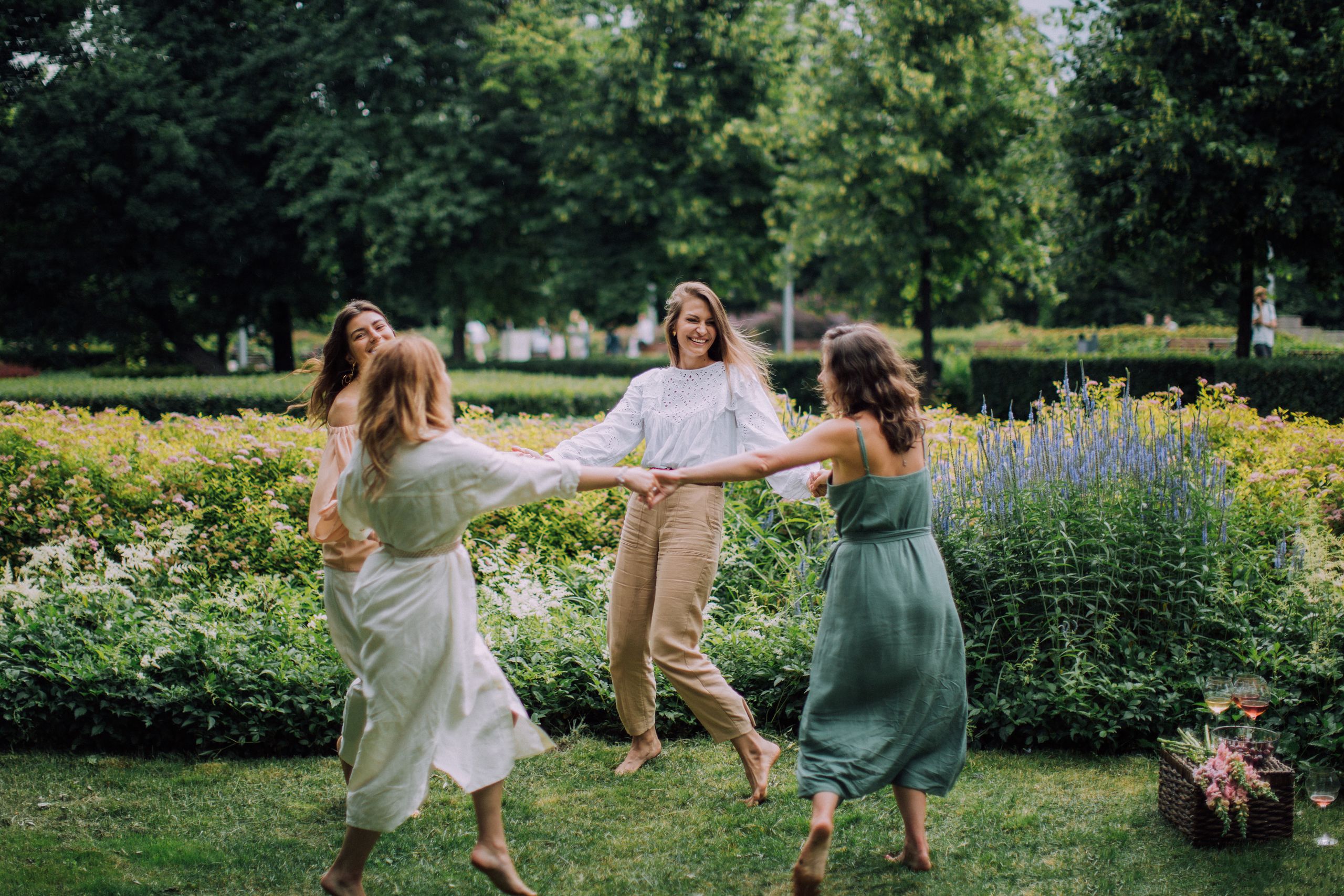 Why Women Need Public Joy - A group of women joyfully dancing in a park on a summer day, exuding happiness.