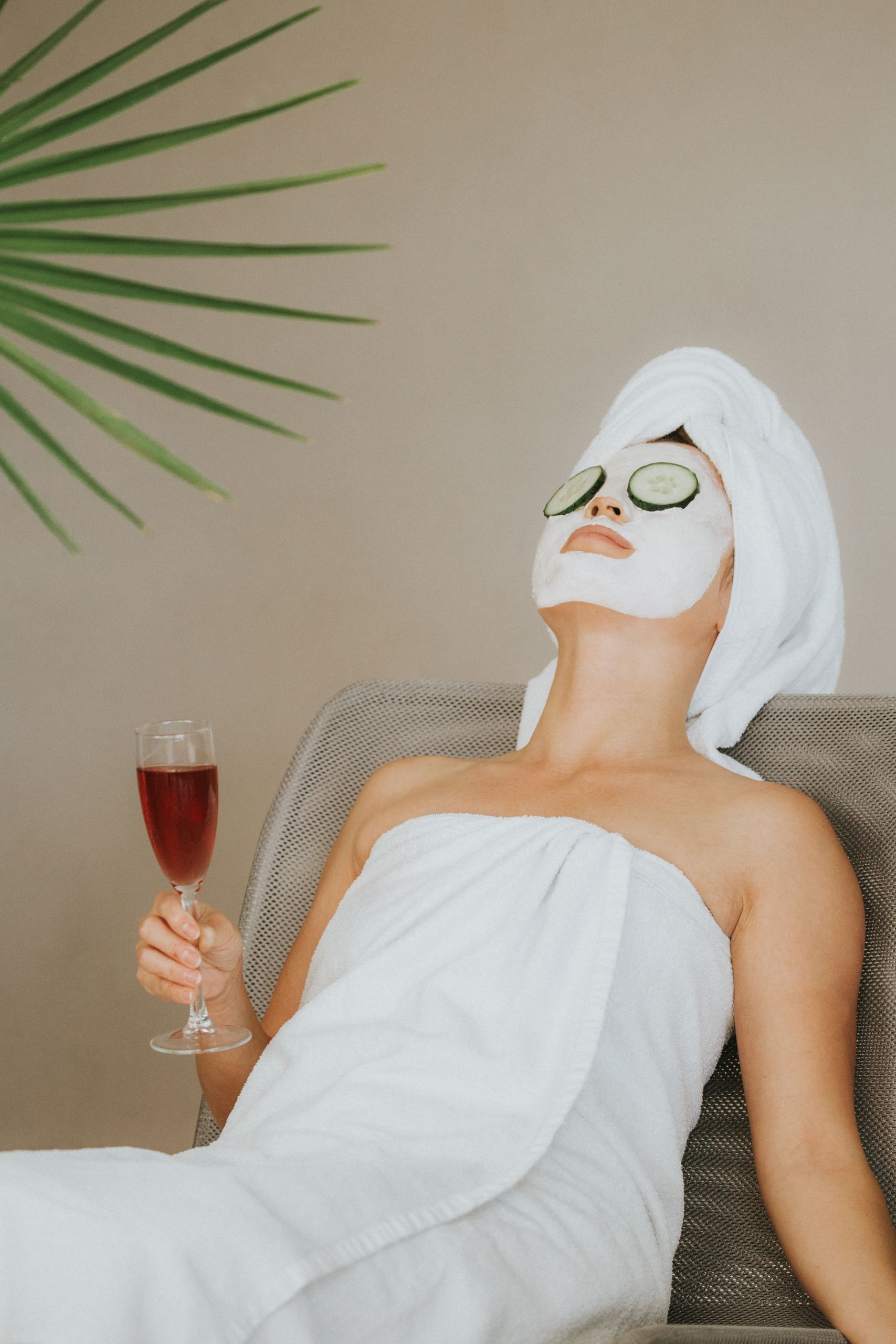 Woman enjoying a spa day with face mask, wine, and relaxation. Perfect for wellness themes.